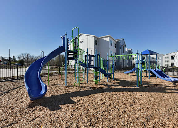 A playground with a blue slide and a green climbing frame.