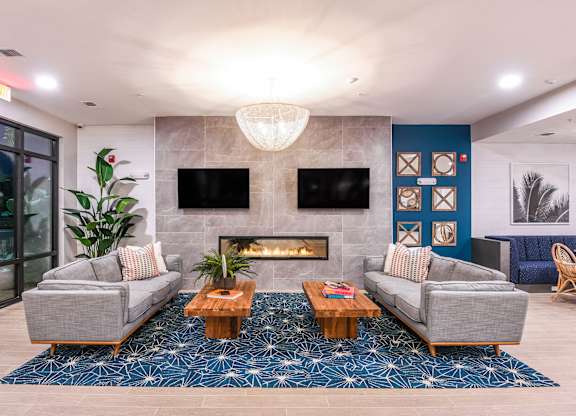 A modern living room with a fireplace and grey couches.
