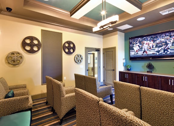 A room with a row of chairs and a television playing a football game.