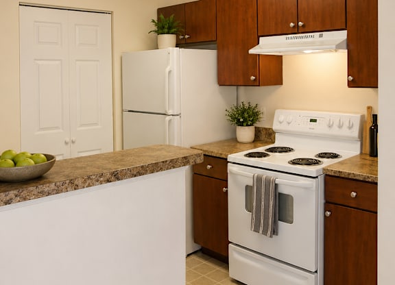 A white stove and refrigerator in a kitchen with brown cabinets.