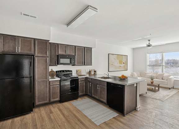 A modern kitchen with dark brown cabinets and black appliances.