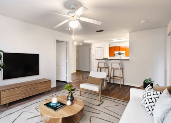 A living room with a flat screen TV, a white couch, and a coffee table.