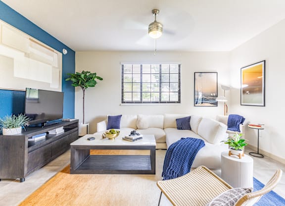 A living room with a white couch and a wooden coffee table.