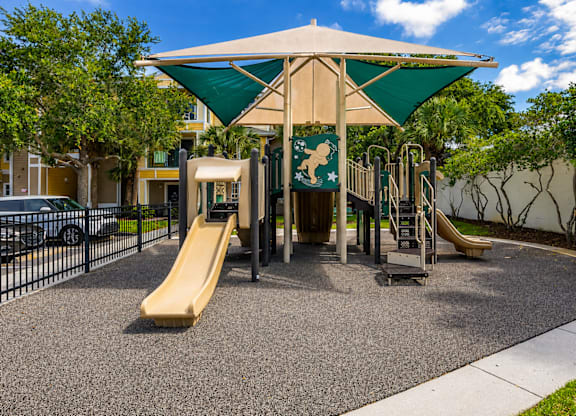 A playground with a yellow slide and a green canopy.