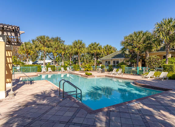 A swimming pool surrounded by palm trees and lounge chairs.