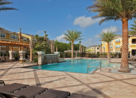 A pool surrounded by palm trees and sun loungers.