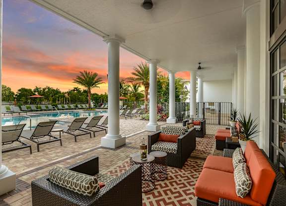 Covered veranda seating by the pool at Palm Ranch Apartments in Davie, FL