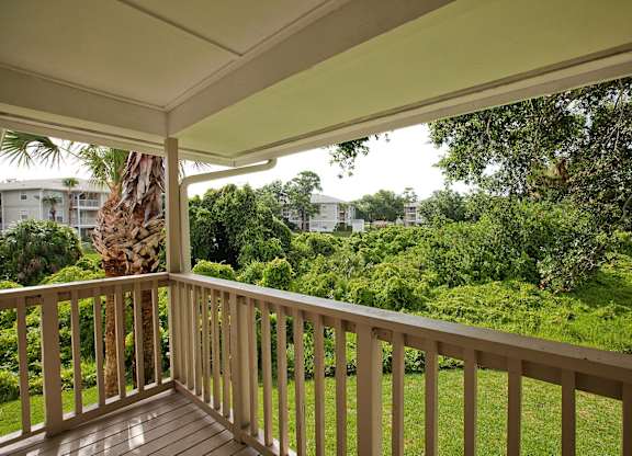 A balcony with a view of a lush green garden and trees.