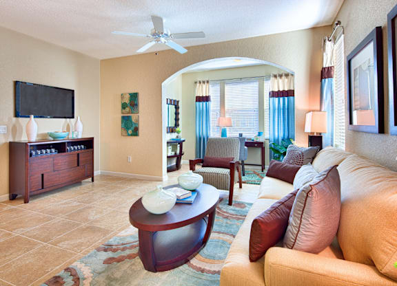 A living room with a tan couch and a wooden coffee table.