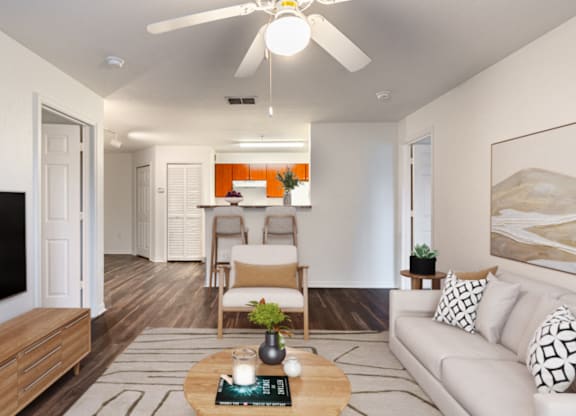 A living room with a couch, a coffee table, and a ceiling fan.