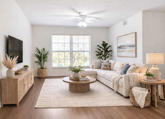 A living room with a white couch, wooden coffee table, and a large window.