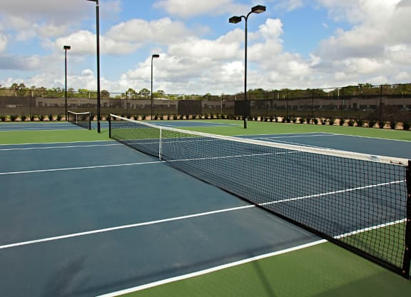 A tennis court with a net and two light poles.