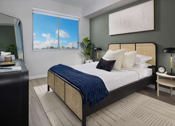 A bedroom with a large bed and a window showing a blue sky.