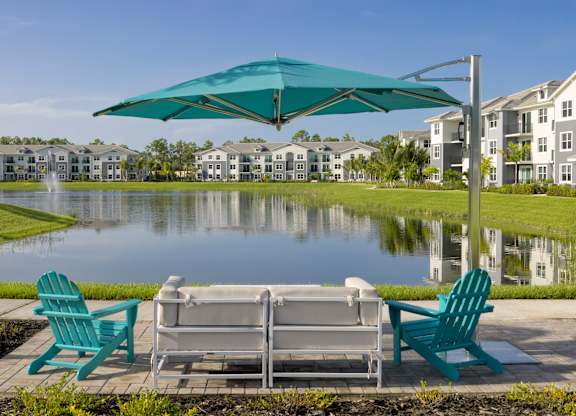 Lakeside Seating with Chairs and an Umbrella at Everly Apartments in Naples, FL