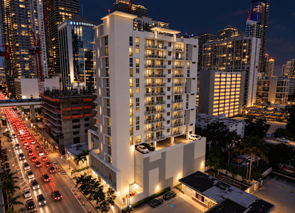 A nighttime cityscape with a tall white building in the foreground.