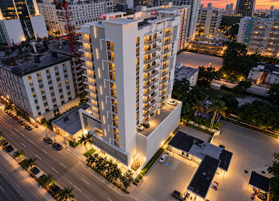 A tall white building with a parking lot in front of it.