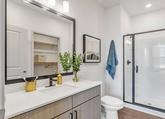a bathroom with a shower, a sink, and a mirror at Apex apartments in Colorado Springs, CO
