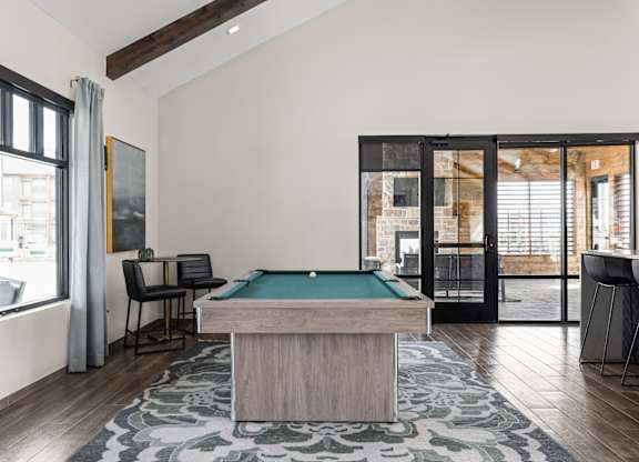 a pool table in a living room with a view of a patio