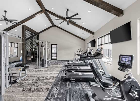 a gym with treadmills and weights and a tv