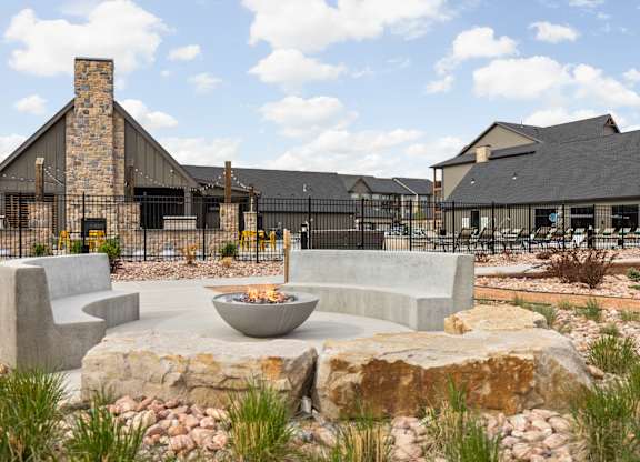 a patio with chairs and a fire pit in front of a building