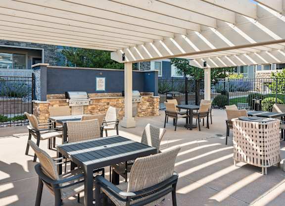 A patio with tables and chairs under a white canopy.