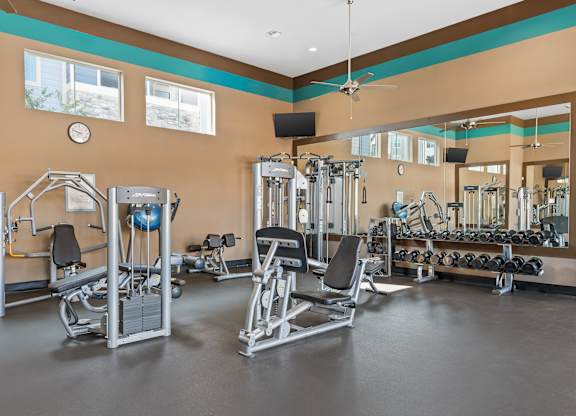 A gym with a variety of equipment including weights and a bench.