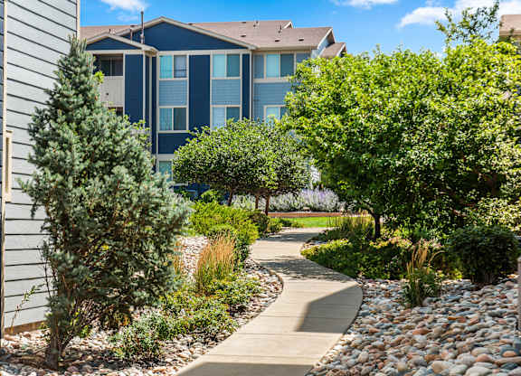A pathway leads through a landscaped area with a building in the background.
