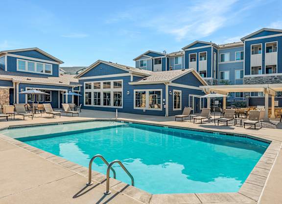 A large swimming pool in front of a building with a blue sky in the background.