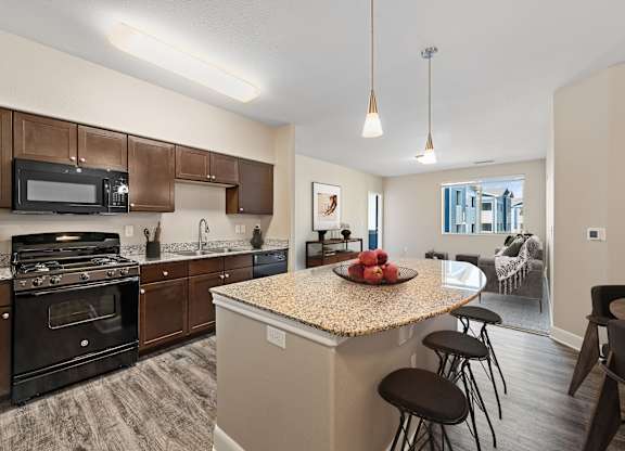 A kitchen with a granite countertop and bar stools.