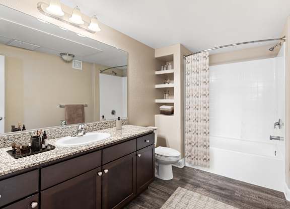 A bathroom with a sink, mirror, toilet, and shower.