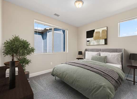 A bedroom with a bed, nightstand, and a plant.