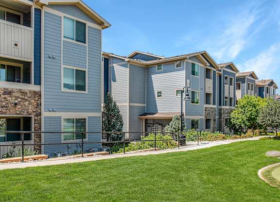 A row of modern townhouses with a well-maintained lawn in front.
