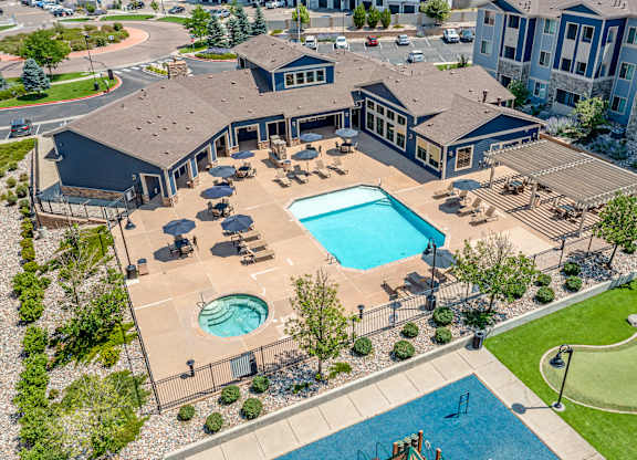 A large outdoor swimming pool surrounded by a fence and lounge chairs.