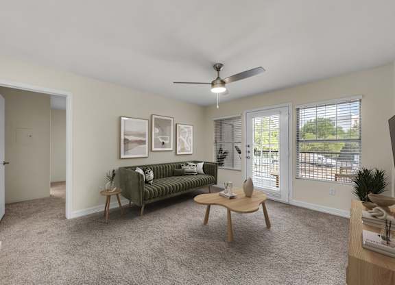 A living room with a green couch, a wooden coffee table, and a ceiling fan.