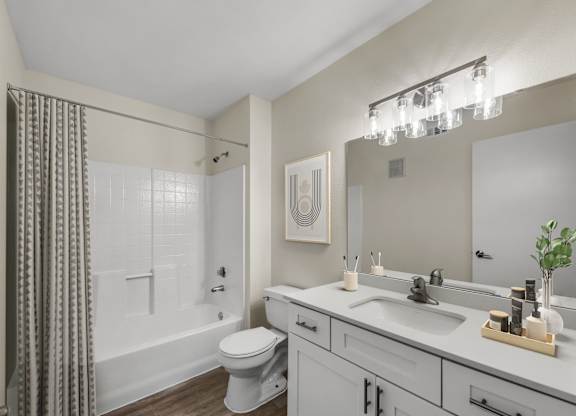 A bathroom with a white toilet, a white sink, and a white bathtub with a grey shower curtain.