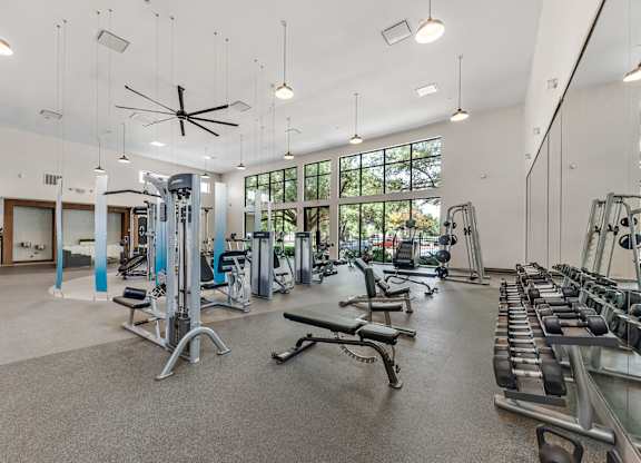 A spacious gym with a variety of equipment and a ceiling fan.