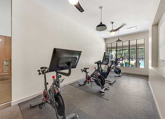 A room with exercise bikes and a ceiling fan.
