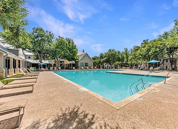 A large swimming pool surrounded by trees and a clear blue sky.