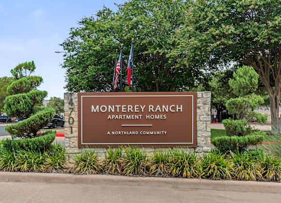 A sign for Monterey Ranch Apartment Homes is displayed in front of some trees.