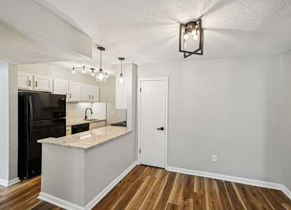 A kitchen with a black refrigerator and white cabinets.