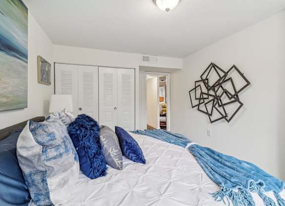 a bedroom with white walls and a bed with blue blankets and pillows at Oaks at Oxon Hill, Oxon Hill, Maryland