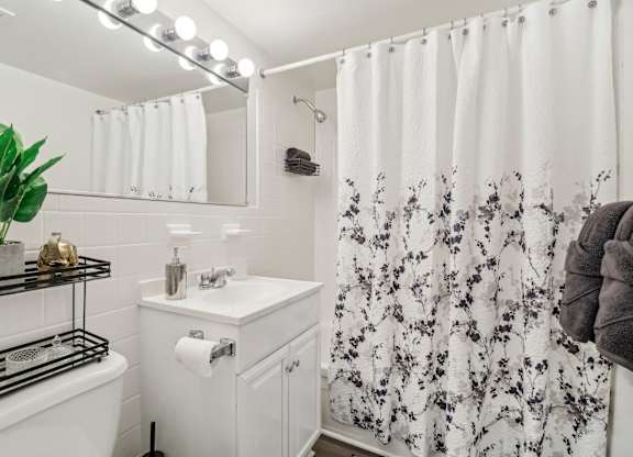 a white bathroom with a shower curtain and a sink at Oaks at Oxon Hill, Oxon Hill, Maryland