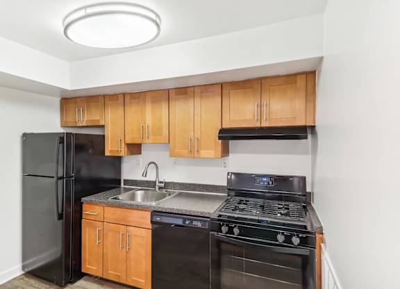 a kitchen with black appliances and wooden cabinets and a black refrigerator at Oaks at Oxon Hill, Oxon Hill, Maryland