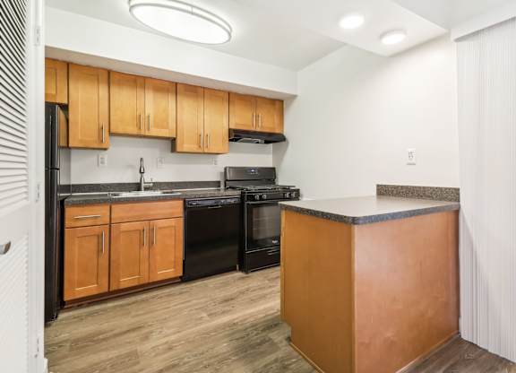 a kitchen with black appliances and wooden cabinets and a counter top at Oaks at Oxon Hill, Oxon Hill, Maryland