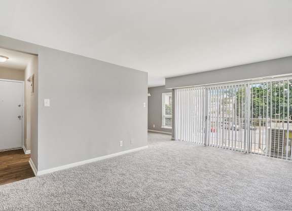 an empty living room with a sliding glass door to a balcony at Andrews Ridge Apartments, Suitland, MD
