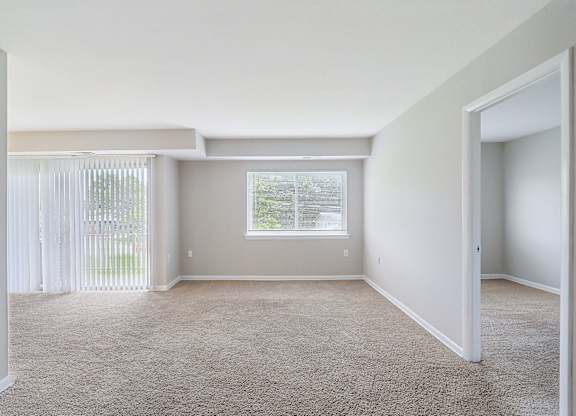 an empty living room with white walls and a window at Andrews Ridge Apartments, Suitland, MD