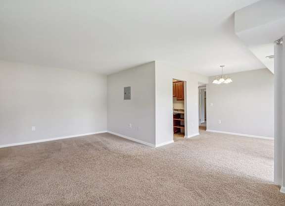 an empty living room with white walls and carpet at Andrews Ridge Apartments, Suitland, MD
