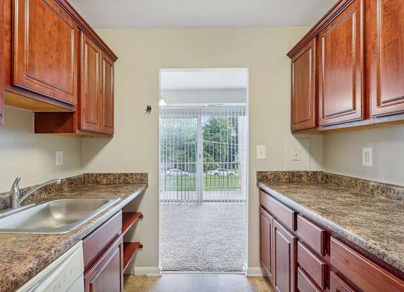 a kitchen with wooden cabinets and granite counter tops and a sliding glass door at Andrews Ridge Apartments, Suitland, MD