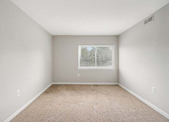 an empty room with carpet and a window at Andrews Ridge Apartments, Suitland, MD