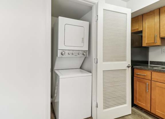 a white washer and dryer in a kitchen with wood cabinets at Oaks at Oxon Hill, Oxon Hill, Maryland